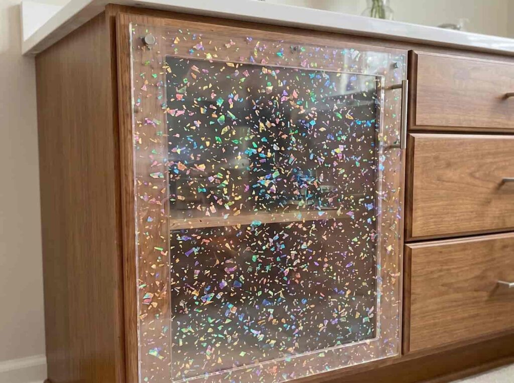 Clear decorative acrylic panel featuring embedded holographic flakes, utilized as a custom cabinet door for premium interior design.