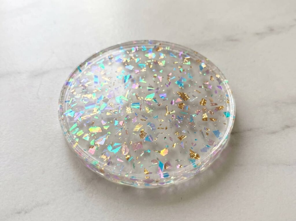 Custom circular transparent acrylic block with embedded iridescent flakes, manufactured by Grandview Acrylic for bespoke design applications.